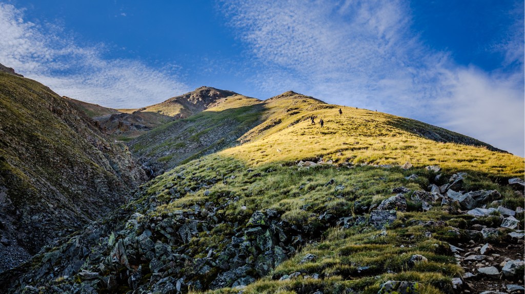 people hiking up a mountain at sunrise
